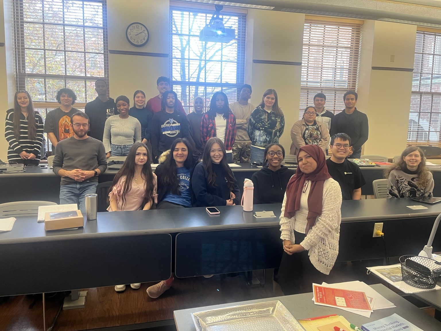 Students and their instructor gathered around classroom desks.